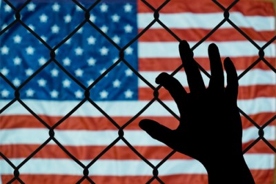 american flag with hand behind fence
